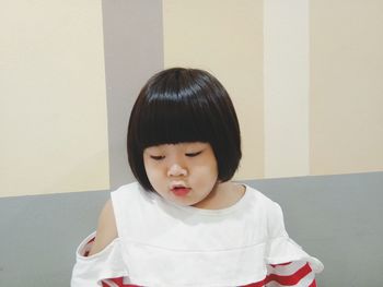 Portrait of cute girl against wall at home