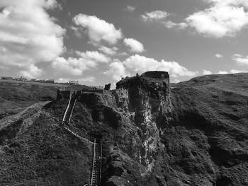 Built structure on landscape against cloudy sky