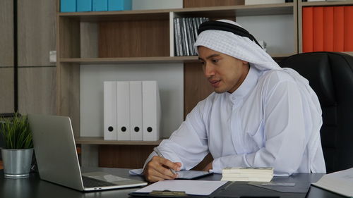 Side view of woman using laptop at table
