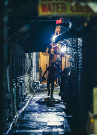 Rear view of man walking on footpath amidst buildings in city