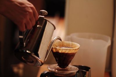 Close-up of hand pouring coffee in cup