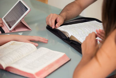 Midsection of woman reading book on table