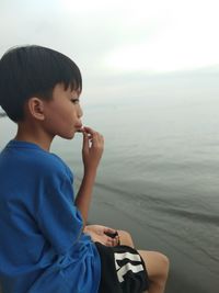 Boy looking at sea against sky