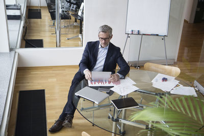 Successful businessman sitting in board room using digital tablet