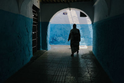 Rear view of man walking in tunnel