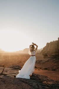 Woman standing on desert against clear sky