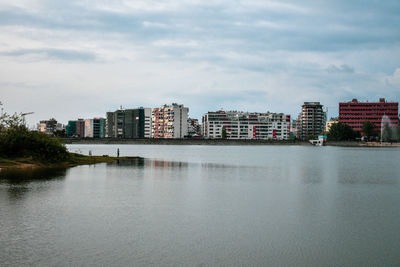 Buildings by river against sky in city