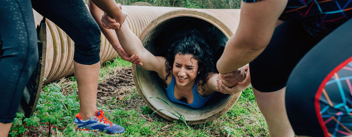 Friend removing woman from pipe while exercising on land