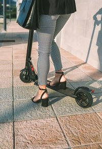 Low section of businesswoman riding electric push scooter on sidewalk