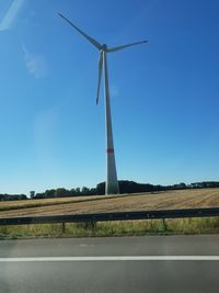 Windmill on field against clear blue sky