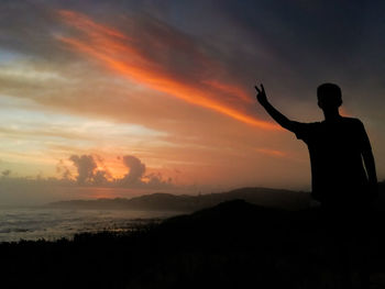 Sunset with mans arms stretched out wide