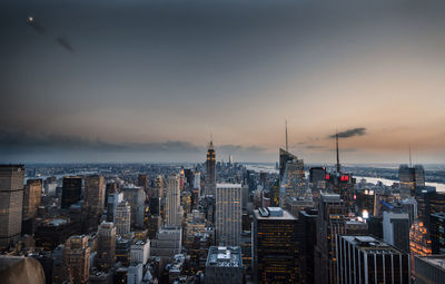 Empire state building amidst cityscape against sky during sunset