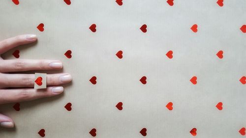 Cropped image of woman hand on paper with heart shapes