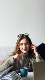 Portrait of young woman using mobile phone while sitting at home