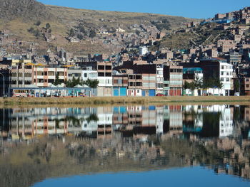 Buildings by lake in city against sky