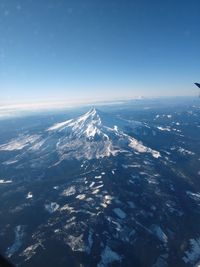 Aerial view of snowcapped mountain against blue sky