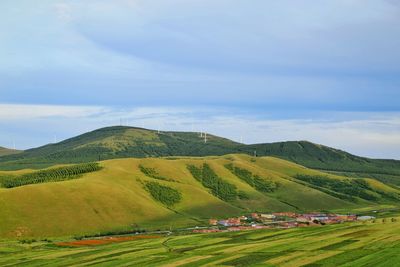 Scenic view of field by mountain against sky