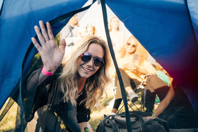 Portrait of smiling woman with friends looking in tent at festival