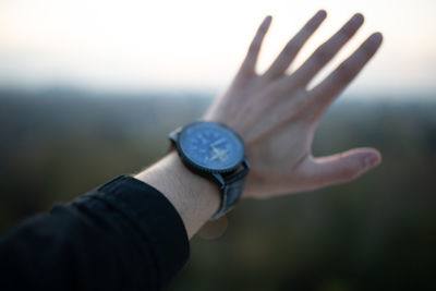 Cropped hand of man wearing watch gesturing outdoors