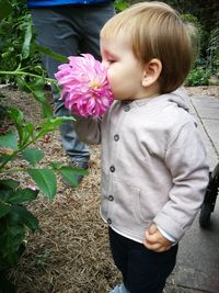 Cute baby boy smelling pink flower in park