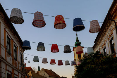 Low angle view of lanterns hanging by building against sky