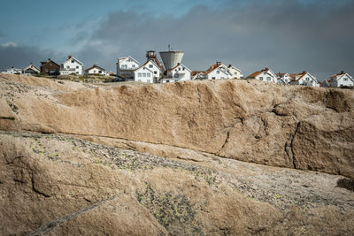 Cityscape on rock formation against cloudy sky