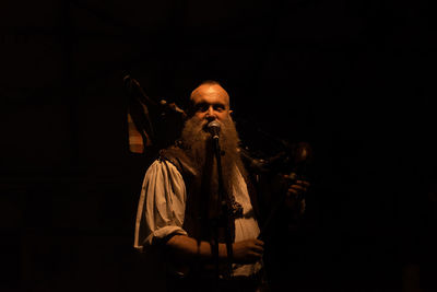 Man with umbrella standing against black background