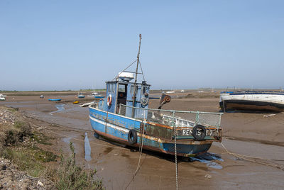Fishing boat moored on shore against clear sky