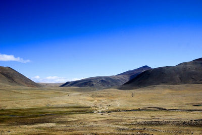 Scenic view of landscape and mountains against blue sky
