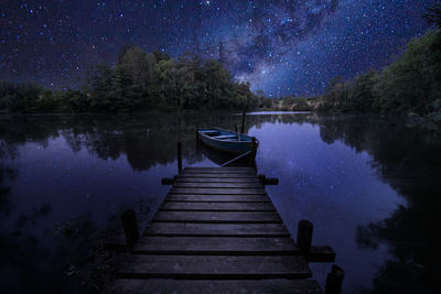 Pier over lake against sky at night