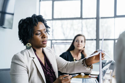 Businesswoman explaining wind turbine model to colleagues in office