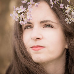 Close-up of thoughtful young woman wearing flowers on hair