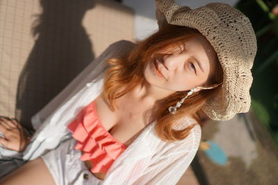 High angle portrait of young woman wearing hat while winking