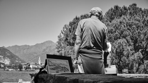 Rear view of men sitting on mountain against clear sky