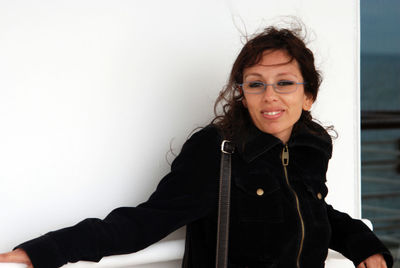 Portrait of smiling young woman standing against wall