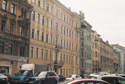 Cars on road by buildings against sky