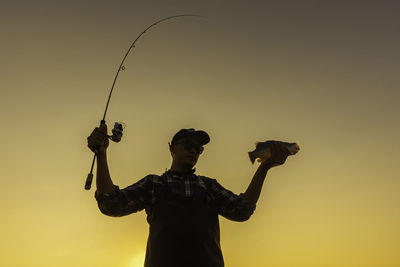 Low angle view of man photographing against sky during sunset