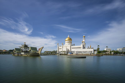 View of building by river against cloudy sky