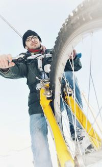 Low angle view of man with bicycle on snow