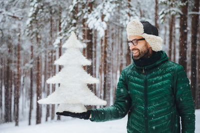 Young man standing against snow covered trees during winter