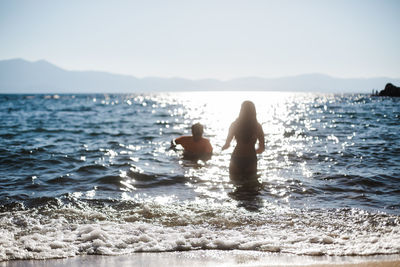 Swimmers in a blue lake with sunshine and sand for mountain getaways