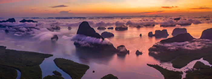 Panoramic view of rocks and sea against sky during sunset