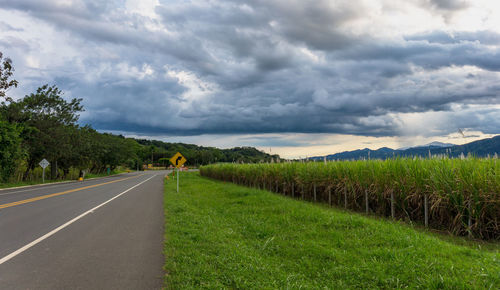 Road amidst field against sky