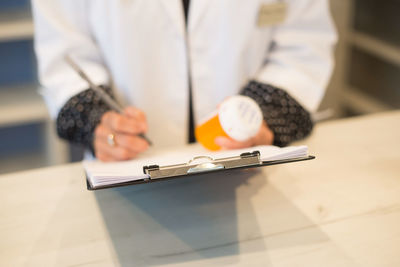 Midsection of woman reading book on table