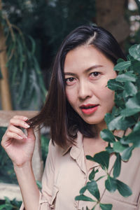 Portrait of a beautiful young woman holding plant