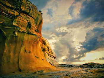 Low angle view of rock formation against cloudy sky