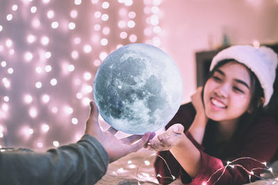 Cropped hand giving illuminated decoration to smiling woman