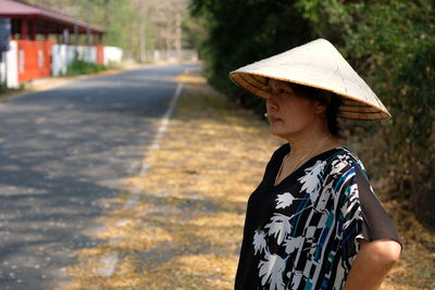 Mature woman wearing asian style conical hat on road during autumn