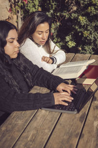 Portrait of young woman using laptop, young mother helps daughter do college work, in home garden