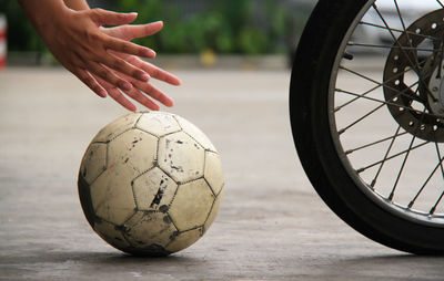 Cropped hands holding soccer ball on road